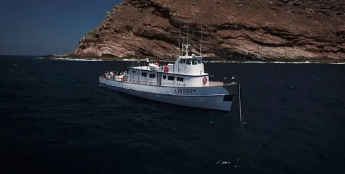 The Liberty from Fisherman’s Landing fishing beside a rocky island